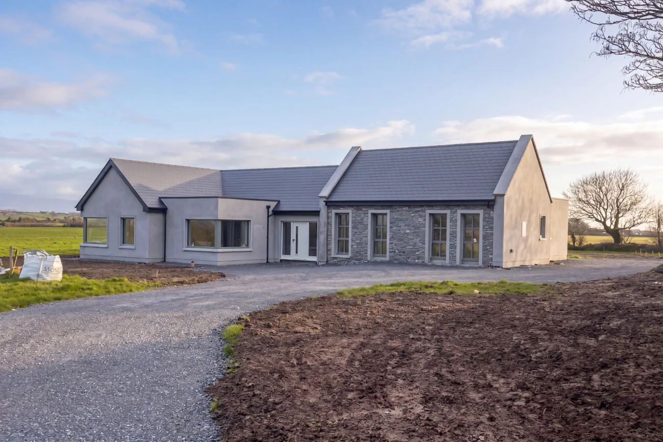 Single-storey home with a slate roof and stone-clad entrance in the Irish countryside